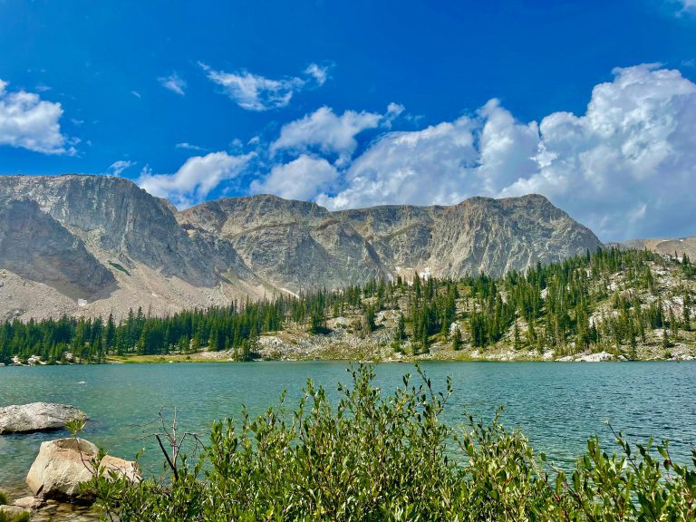 Medicine Bow Mountains and a serene lake in Wyoming, with trees and rocks.
