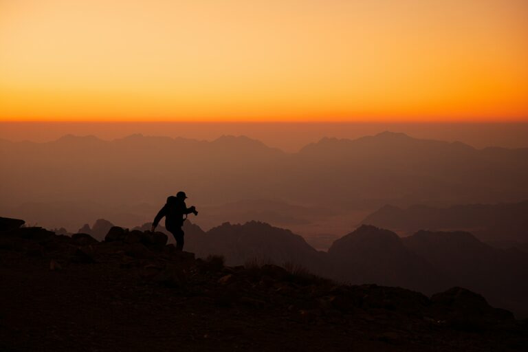 A hiker stays cool under the summer sun on a trail, practicing hiking in hot weather safety.